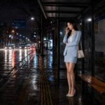 비 오는 밤 버스정류장에서 한국인 여성 직장인이 남자 직장 동료의 전화를 받으며 호감인지 예의인지 고민하는 장면